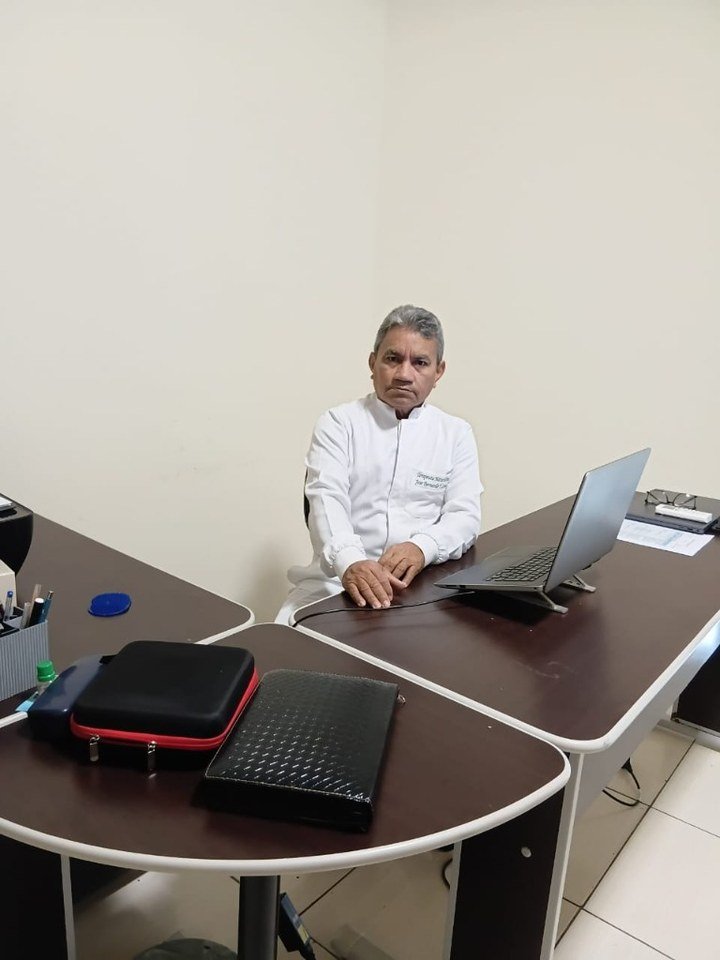 José Bernardo, terapeuta naturalista, sentado em seu consultório atrás da mesa